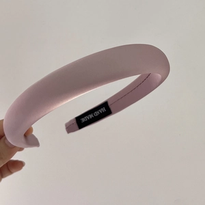 Detail of pink padded satin headband with HAND MADE label showing premium texture