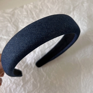 Close-up of a padded denim headband in deep blue showing its textured fabric and inner lining