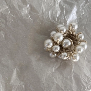 Detail of elegant pearl cluster hair tie with woven beige elastic and glossy finish