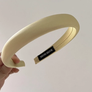 Detail of cream yellow sponge headband with handmade label and satin fabric texture