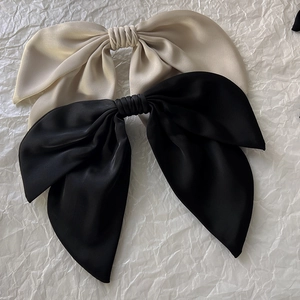 Detailed view of champagne and black satin bow hair clips on a textured background