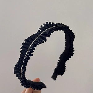 Detail of black pleated fabric headband featuring a delicate sparkling rhinestone chain