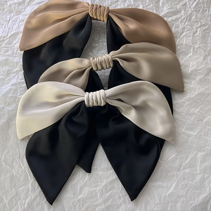 Detailed macro view of large satin bow hair clips in black and champagne color tones