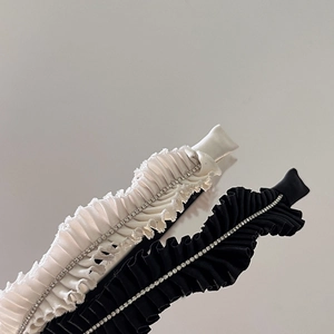 Detail of pleated fabric headband with shiny rhinestones in black and beige colors