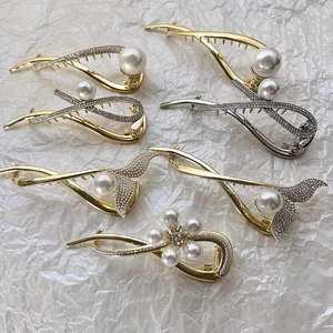 Vue à plat de pinces à cheveux en alliage avec perles et strass sur fond blanc texturé
