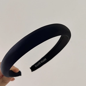 Detail of a padded black headband with high-quality fabric texture and Hand Made label