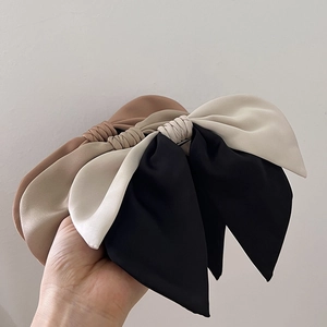 Detailed view of elegant bow hair clips in black, beige, and khaki satin fabric textures