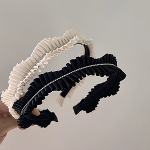 Detail of pleated satin headbands with shimmering rhinestones in black and cream beige