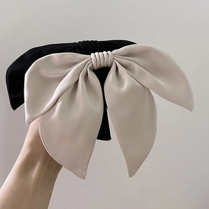Detail of large satin bow hair clip in elegant black and champagne silk fabric