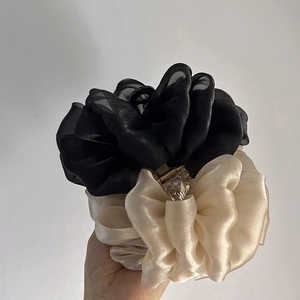 Détail de grandes pinces à cheveux en mousseline plissée noir et doré champagne