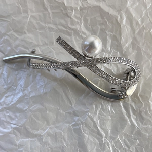 Détail d'une pince à cheveux argentée ornée de strass brillants et d'une perle centrale
