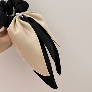 Detailed view of champagne and black satin ribbon hair tie with elegant white pearl accents