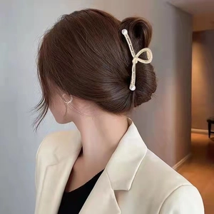 Elegante molletta per capelli in metallo dorato con perle e strass sui capelli di una donna