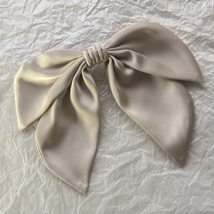 Detailed macro view of high-quality champagne satin fabric French bow hairclip with silk texture