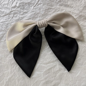 Detail of the high-quality two-tone satin bow hair clip in black and beige silk fabric