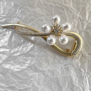 Détail de pince à cheveux élégante en alliage doré avec fleur de perle et strass