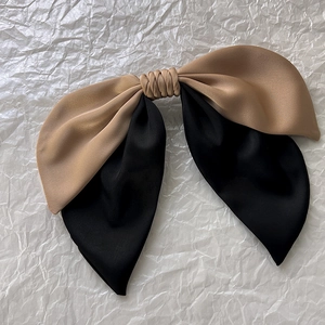 Detail of elegant two-tone khaki and black satin bow hair clip on textured background