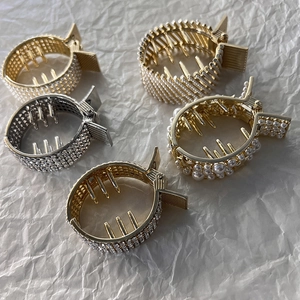 Detail view of rhinestone hair claws in gold and silver with pearls and metal teeth