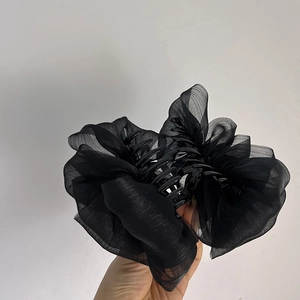 Détail d'une grande pince à cheveux noire avec texture bouffante en organza transparent