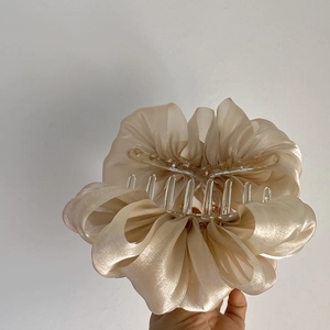 Gros plan sur la grande pince à cheveux en organza champagne avec tissu à volants et griffes