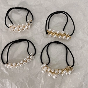 Detail of four French style black elastic hair ties with white pearls and gold accents