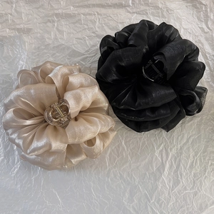 Détail des grandes pinces à cheveux en organza plissé aux tons crème et noir