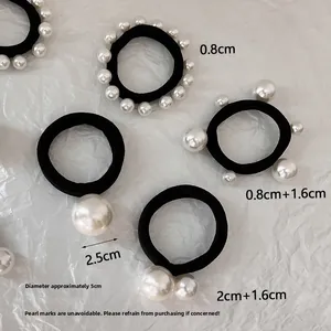 Detailed view of black elastic hair ties featuring various faux pearl sizes on white paper