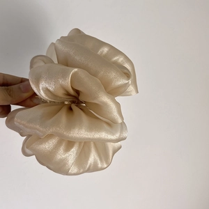 Détail d'une grande pince à cheveux fleur en organza champagne à couches plissées
