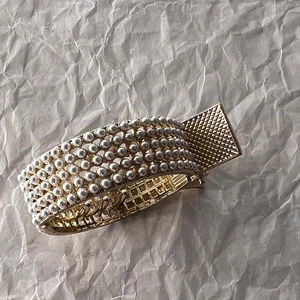 Detail of luxury gold bracelet with six rows of white pearls and quilted clasp texture