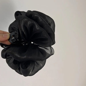 Détail d'une grande pince à cheveux en organza noir montrant la taille réelle en main