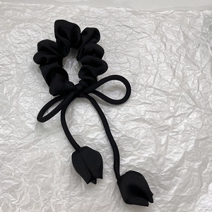 Détail d'un chouchou en satin noir avec un nœud élégant et des pendentifs tulipe