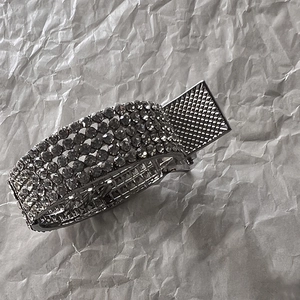 Detailed side view of silver metal hair claw clip with four rows of sparkling rhinestones