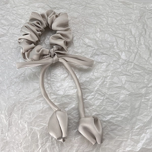 Détail du chouchou en satin champagne avec charme tulipe 3D et ruban long