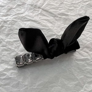Detail of elegant black satin bow hair clip featuring three rectangular grey crystals