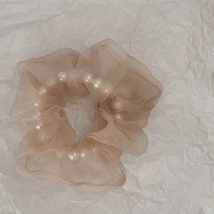 Détail d'un chouchou en organza champagne avec des perles blanches élégantes intégrées