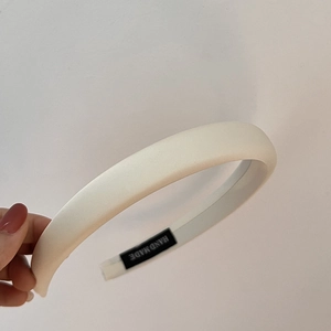 Close-up of beige padded headband showing detailed fabric and Hand Made interior label