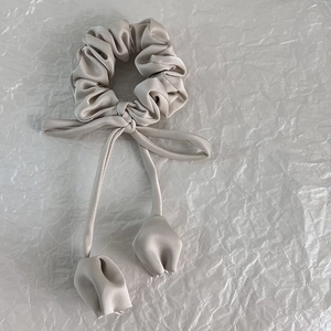 Détail de chouchou en satin champagne avec rubans longs et fleurs de tulipe en 3D