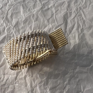 Detail of elegant gold hair claw with multiple rows of fine white pearls on metallic base