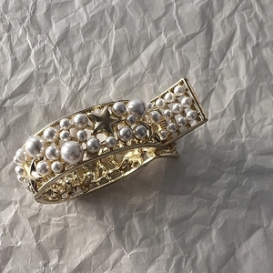 Close-up of golden hair claw clip featuring elegant faux pearls and star charms