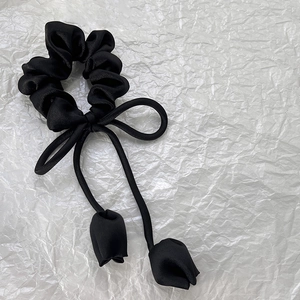 Détail d'un chouchou en soie noire avec pendentifs tulipes élégants et grand nœud