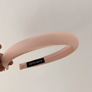 Close-up of pink padded satin headband featuring a black woven Hand Made interior label
