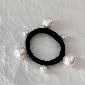 Macro detail of black elastic hair band decorated with six elegant white faux pearls
