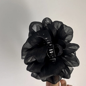 Gros plan d'une pince à cheveux fleur en organza noir avec pétales multicouches