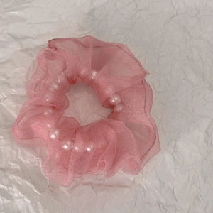 Détail d'un chouchou en organza rose avec perles blanches et tissu en maille plissée