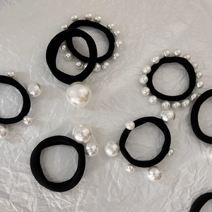 Detailed view of elastic black hair ties with various sizes of elegant white pearls