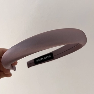 Detail of handmade padded satin headband in lotus pink with artisan woven label