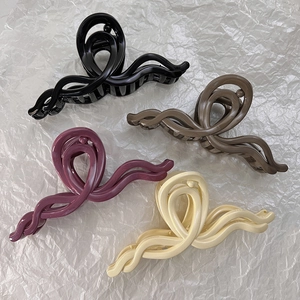Vue macro de quatre pinces à cheveux ondulées en noir, marron, violet et crème clair