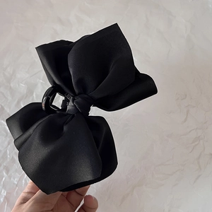 Close-up of a large black satin bow hair claw clip with elegant silk texture