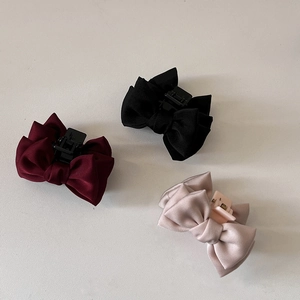 Détail de pinces à cheveux noeud en satin en bordeaux, noir et rose champagne