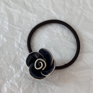 Dettaglio ravvicinato di un elastico per capelli con camelia blu e trama nera